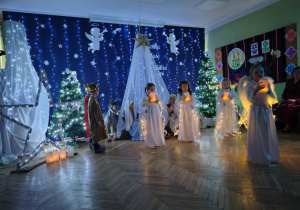 Na zdjęciu dziewczynki w przebraniu aniołków wykonują tanie z lampionami