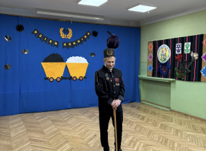 na zdjęciu Pan górnik w stroju galowym, na głowie ma czapkę z purpurowym pióropuszem