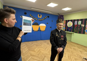 na zdjęciu pan górnik i P Natalia, górnik opowiada jak wygląda flaga górnicza, a p Natalia Prezentuje flagę na obrazku