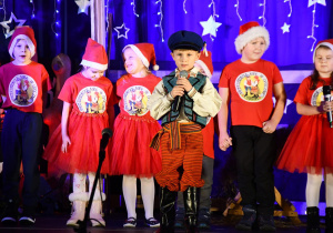 Na zdjęciu na pierwszym planie znajduje się Jaś w stroju ludowym, śpiewa pastorałkę, za nim stoją pozostałe dzieci