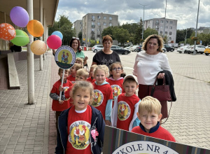 Na zdjęciu dzieci z gr Słoneczniki ubrane w podkoszulki czerwone z logo przedszkola, wraz z Paniami w drodze na Marsz Przedszkolaków