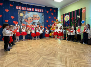 na zdjęciu dzieci z gr pierwszej ubrani na biało czerwono, podczas występu dla babć i dziadków