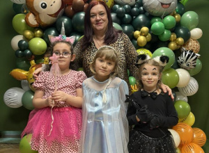 Na zdjęciu Pani Dyrektor wraz z dziećmi przebranymi w rożne stroje karnawałowe, na tle dekoracji balonowej