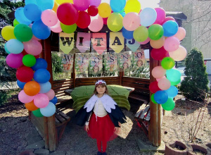 Na zdjęciu Dziewczynka w stroju Bociana na tle dekoracji balonowej