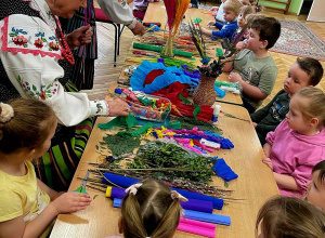 Na zdjęciu Panie twórczynie ludowe w tradycyjnych strojach ludowych, tworzą wraz z dziećmi palmę wielkanocną