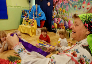 Na zdjęciu twórczyni, przygotowuje dla dzieci kolorowe kwiaty z bibuły