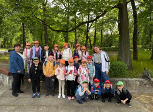 Na zdjęciu dzieci wraz z paniami przed wejściem do zoo, w tle zieleń parku