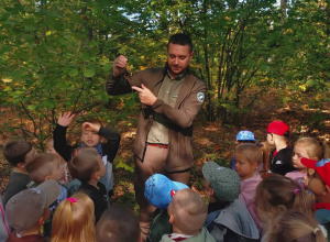 na zdjęciu dzieci wraz z Panem Leśniczym, Pan Leśniczy opowiada dzieciom o budowie drzewa